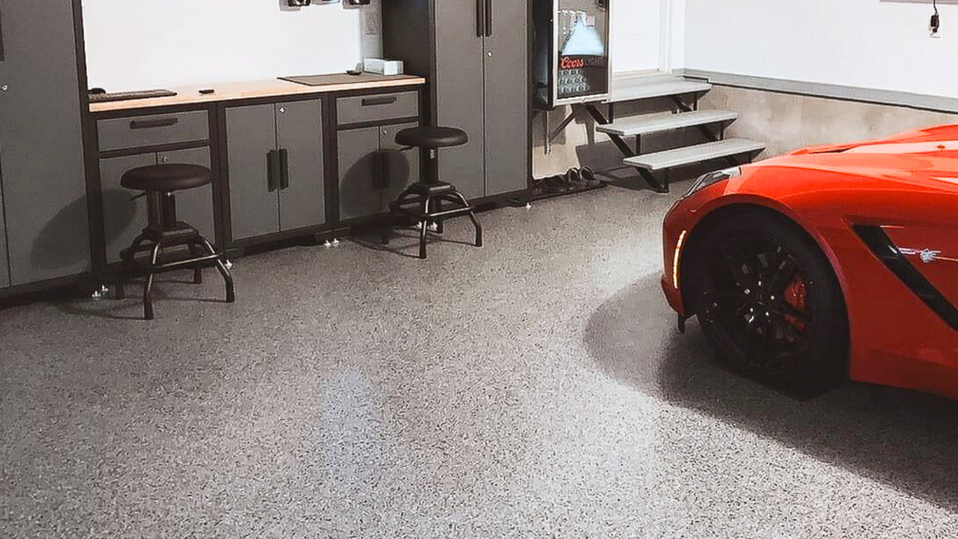 Garage avec sol en résine pailletée grise à flocons noirs et blancs, rangements intégrés et véhicule stationné