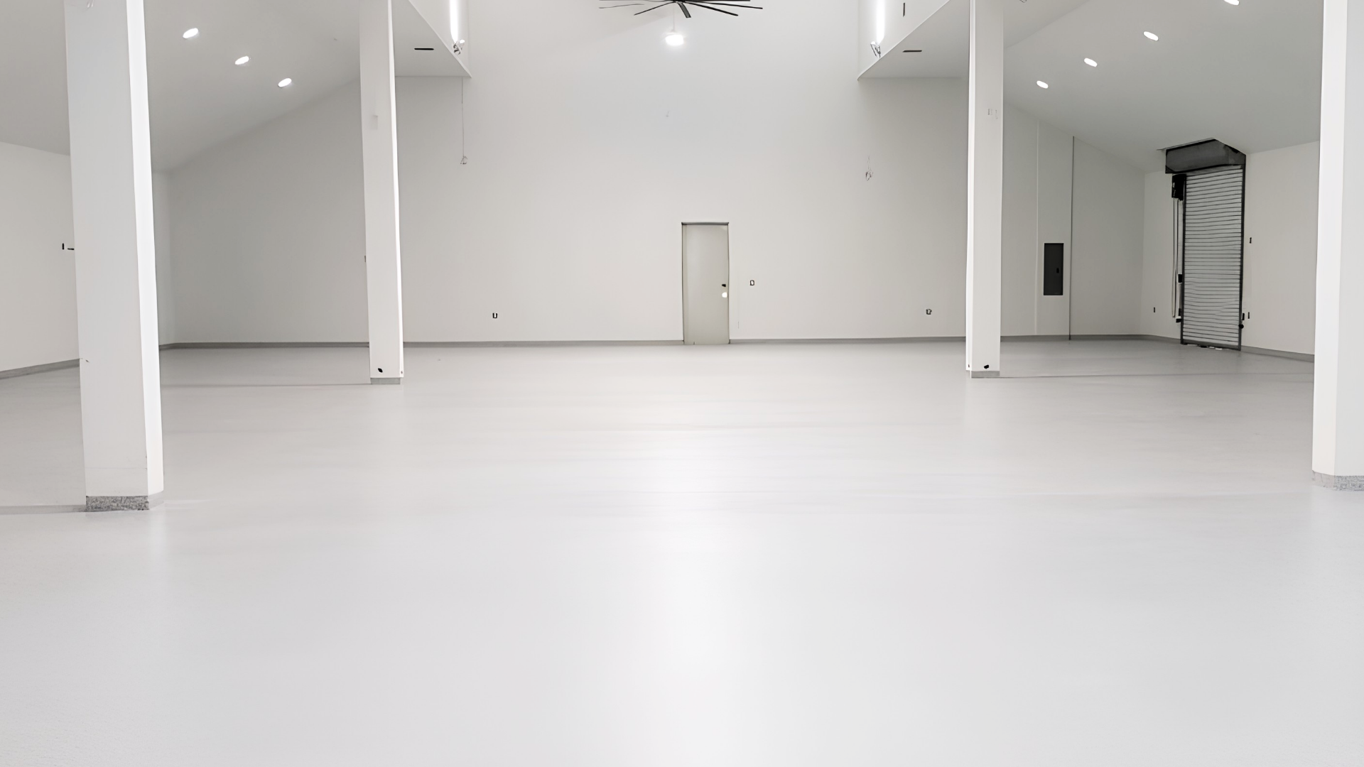 Showroom lumineux avec sol en résine pailletée blanche brillante et murs blancs