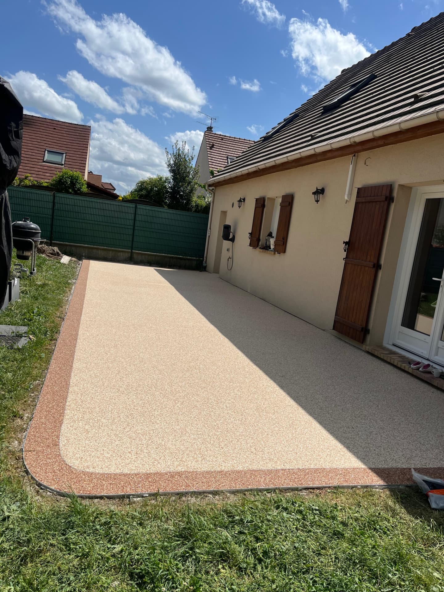 Grande terrasse beige en moquette de pierre avec bordure rouge
