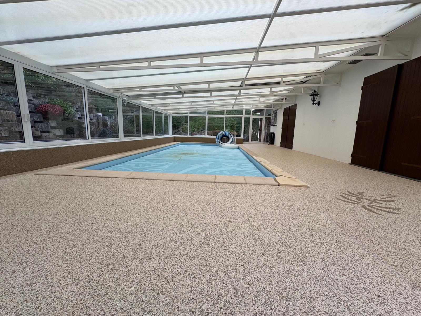 Tour de piscine en moquette de pierre beige avec motif palmier dans une véranda