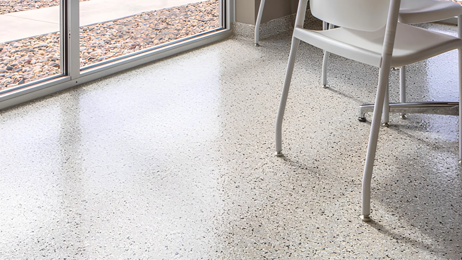 Pièce de vie en rénovation avec sol en résine pailletée blanc à flocons gris, plinthe noyée et grande baie vitrée