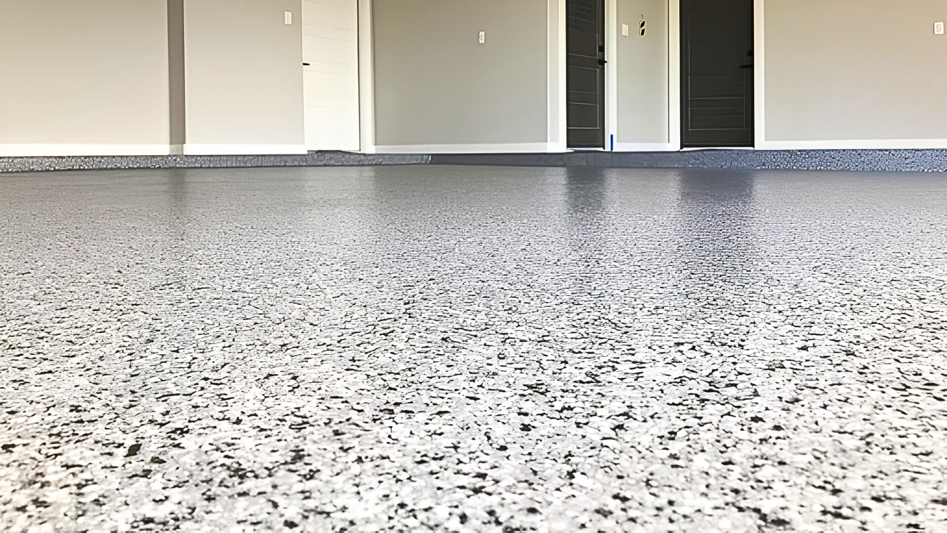 Pièce vide rénovée avec un sol en résine pailletée blanc, gris et noir très brillant et plinthes noyées, posé sur un support existant
